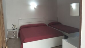 Une chambre avec deux lits, un ventilateur de plafond, une table de chevet et un miroir.