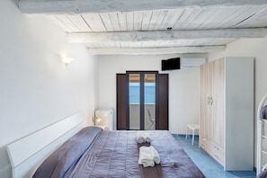Una camera da letto con un letto, un armadio, una televisione e vista mare.