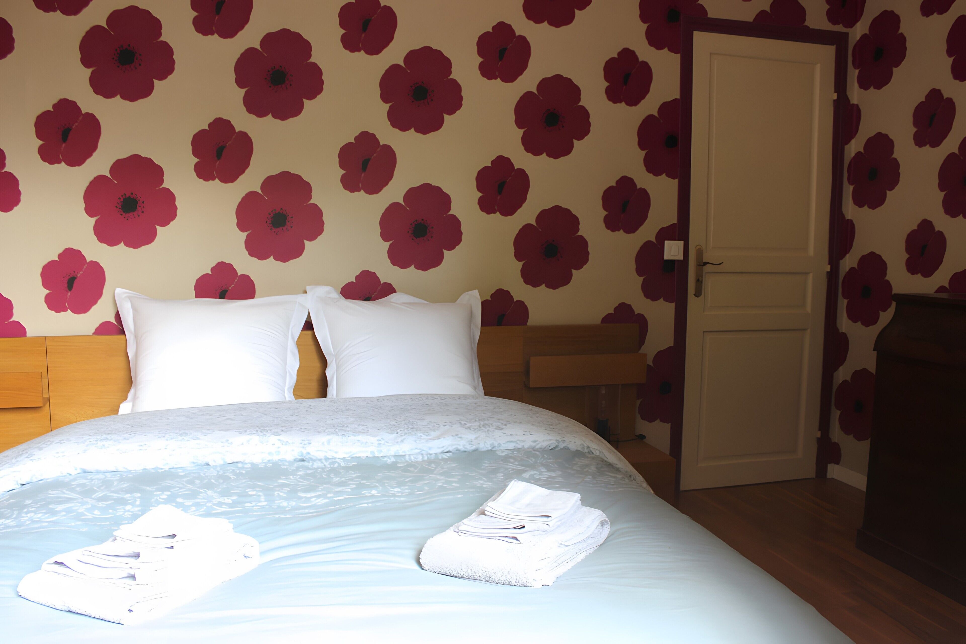 Habitación de hotel con cama, almohadas, cabecero de madera, una puerta y una mesita de noche.