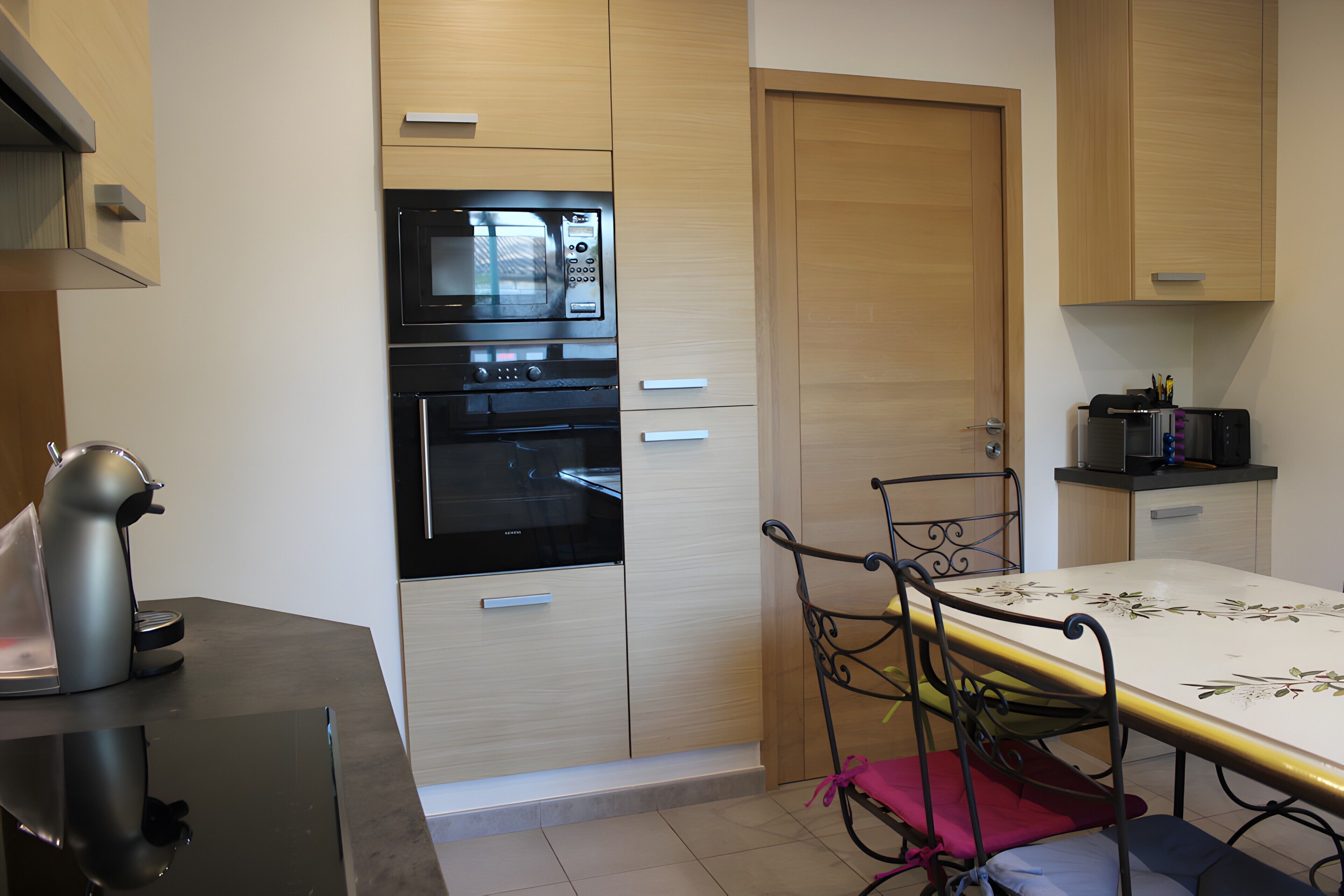 A kitchen with a microwave, oven, and a table with chairs.