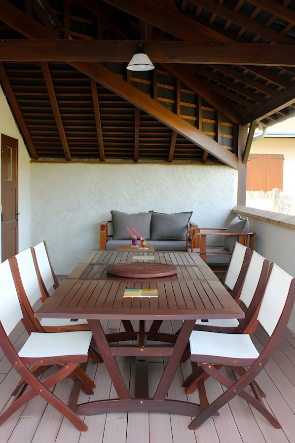 A wooden table with chairs, a sofa, and a ceiling with wooden beams.