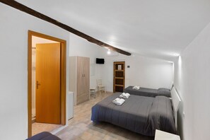 Un dormitori amb dos llits, un armari, un televisor i una porta que dona a una altra habitació.