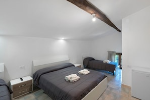Un dormitorio con dos camas, una mesita de noche, un aparador, una lámpara en el techo y una ventana con cortinas.