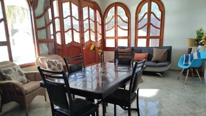 Un comedor con una mesa de vidrio, sillas negras, un sofá y una silla azul.
