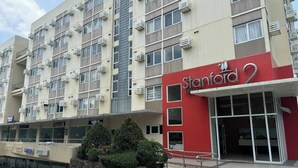 En hotellbyggnad med flera våningar, en röd och beige fasad, luftkonditioneringsanläggningar och en entré som är anpassad för rullstolsburna.