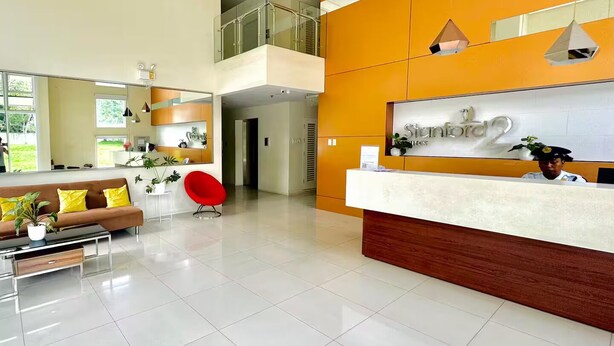 Un área de recepción moderna con un mostrador, una silla roja, un sofá y un espejo grande.
