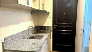 A compact kitchen with a granite countertop, a sink, and a black door. - Calm and Clean Getaway + 400mbps+Netflix+Disney (Silang)