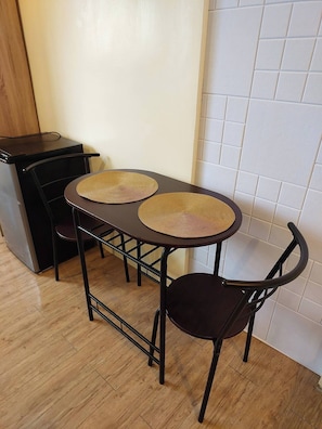 A small dining area with a table and two chairs, a black metal frame, and a woven placemat on the table.