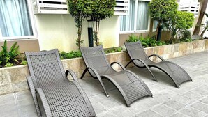 A row of three grey lounge chairs with perforated metal frames, positioned on a tiled patio area. - Z’s Cozy Place (Silang)