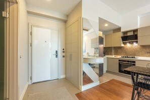 A modern kitchen with a built-in oven, a dining area with a table and chairs, and a white door.