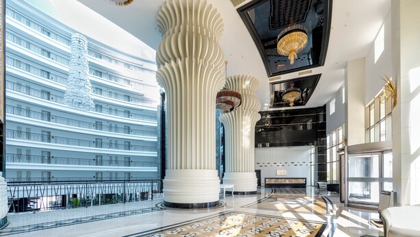 A spacious lobby with high ceilings, large columns, and a grand chandelier. - Maxihomes Snitch (Antalya)