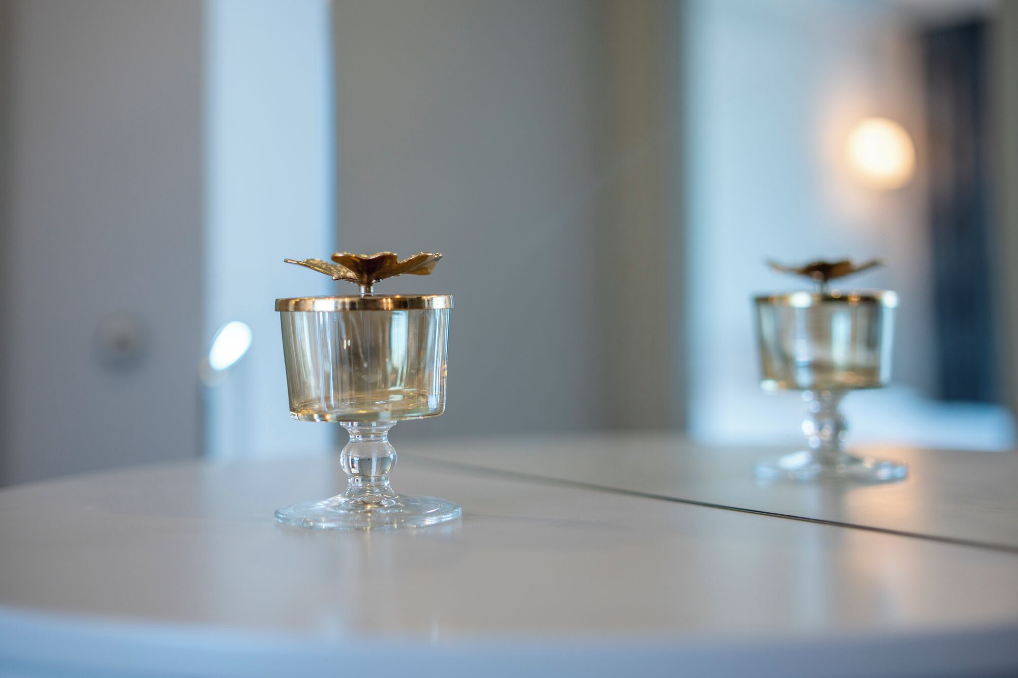 Two clear glass vases with gold accents on a reflective surface.