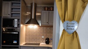 Una cucina con elettrodomestici in acciaio inossidabile, una parete a mosaico di mattoni e un cartello a forma di cuore con la scritta 'Home Sweet Home'.