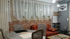 Zona pranzo con parete in mattoni, un tavolo con sedie e un divano con coperta a quadri.