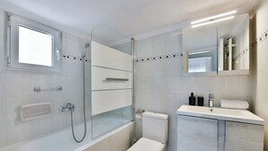A modern bathroom with a glass-enclosed shower, a white toilet, and a vanity with a mirror. - Porto Sea View Apartments - Ermou 61  (Thessaloniki)