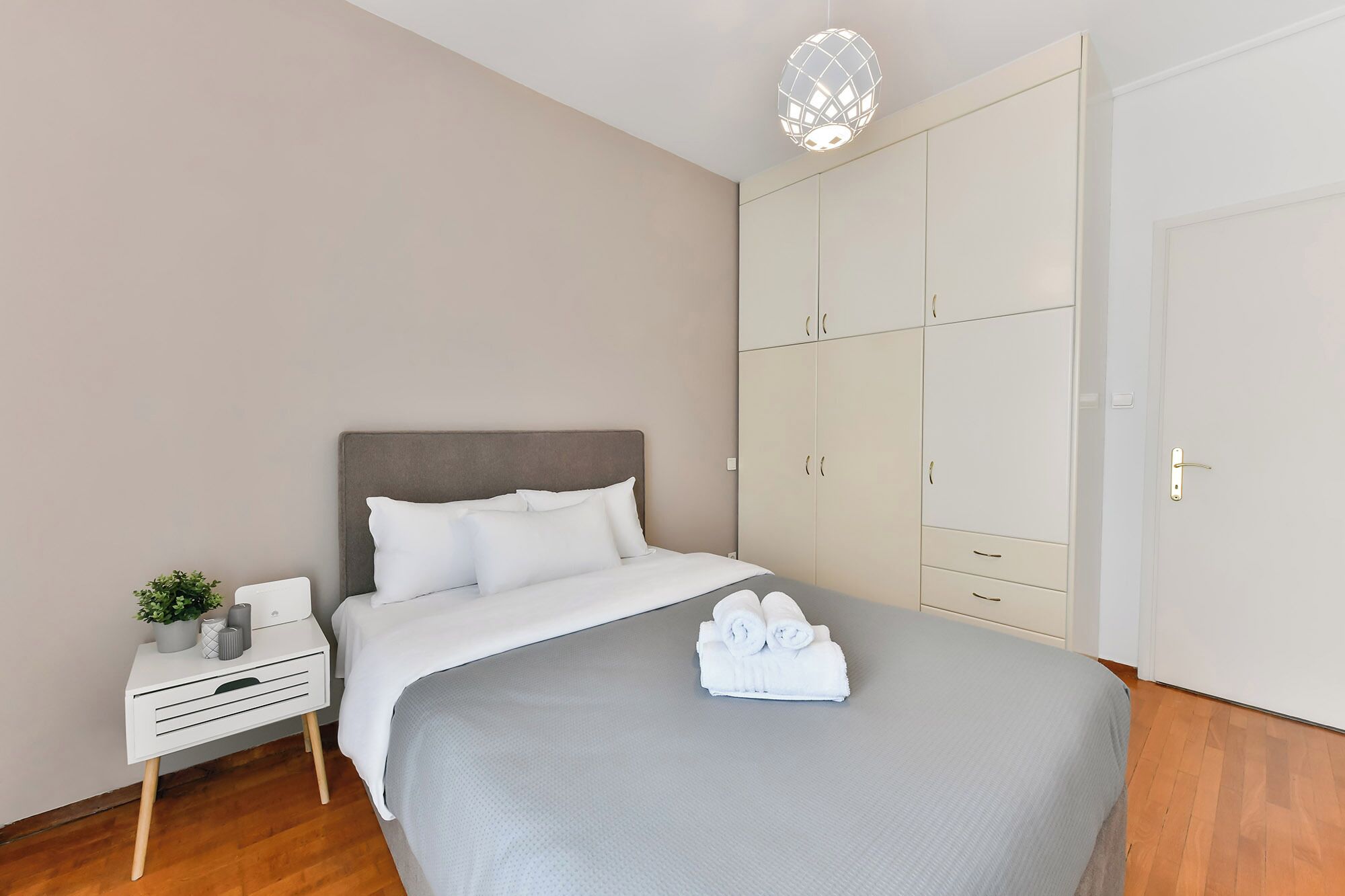 Un dormitorio con cama, mesita de noche, armario e iluminación colgante.