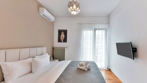 A modern bedroom with a bed, air conditioning unit, radiator, and a TV mounted on the wall. - Porto Sea View Apartments - Ermou 61  (Thessaloniki)