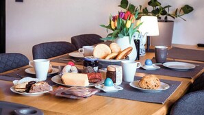 A breakfast setting with various pastries, a vase of tulips, and a teapot on a table. - Apartment 'Ferienwohnung Sußebach mit 80 qm' (Vöhringen)