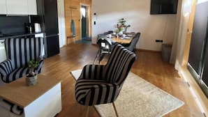 A modern kitchen with white cabinets, a black refrigerator, and a striped chair. - Apartment 'Ferienwohnung Sußebach mit 80 qm' (Vöhringen)