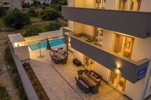 Een modern hotel met een zwembad, terras en een goed verlicht balkon.