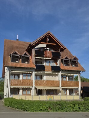 Un edificio de varios pisos con balcones, techo de tejas y un letrero que indica un restaurante.