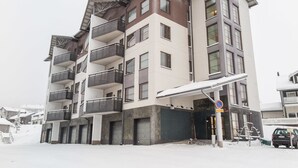 Un immeuble à plusieurs étages doté de balcons, d’une entrée couverte et d’un panneau indiquant qu’il est interdit de se garer.