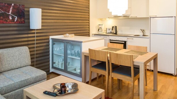 Un espace de vie compact comprenant un coin cuisine, un canapé, une table à manger avec des chaises et un réfrigérateur.