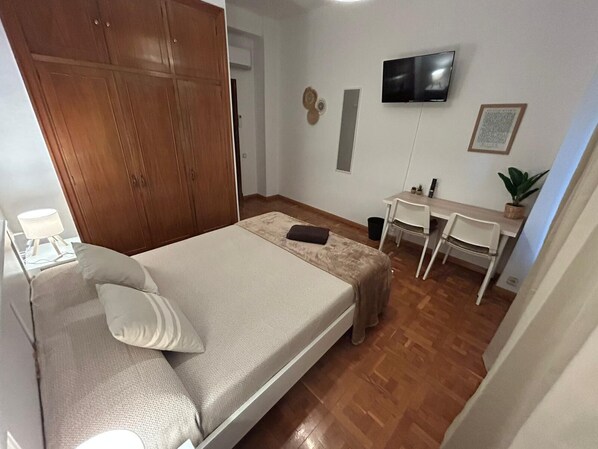 A bedroom with a bed, a desk, a chair, a TV, and a wardrobe. - Rooms Rey junto a Plaza España (Madrid)