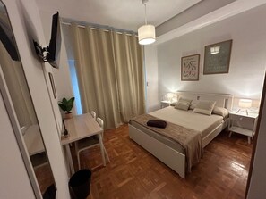 Une chambre d’hôtel avec un lit, des tables de chevet, un bureau et une chaise.