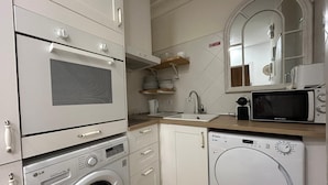 A compact kitchen with a washing machine, microwave, and a sink. - Rooms Rey junto a Plaza España (Madrid)
