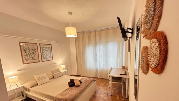 A bedroom with a bed, bedside tables, a desk, and a chair. - Rooms Rey junto a Plaza España (Madrid)