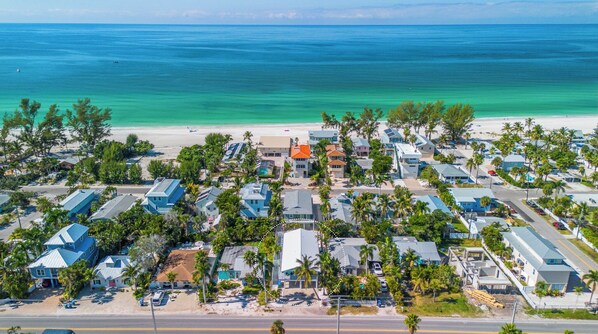 Vista aérea de una zona residencial costera con casas, una playa y un océano azul y transparente.