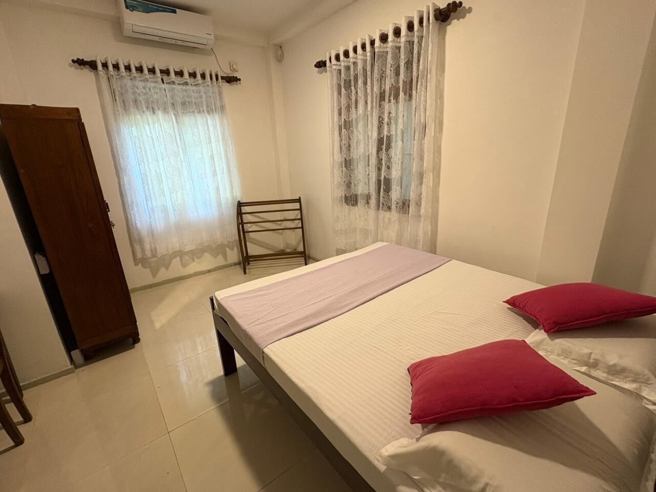 Une chambre à coucher avec un lit, deux oreillers, une chaise et une armoire en bois.