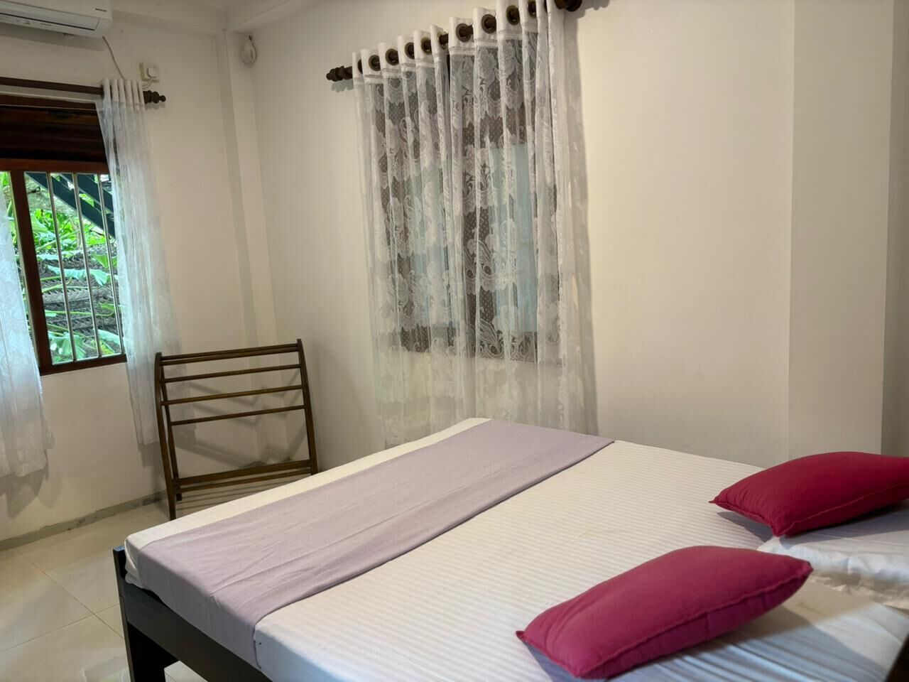 A bedroom with a bed, a chair, and a window with curtains.