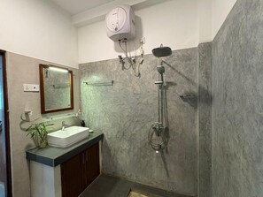 Baño con lavamanos, espejo, ducha y toallero.