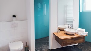 A modern bathroom with a toilet, a sink with a bowl, and a mirror. - Louis & Louise Apartments & Penthouses  (Bremen)