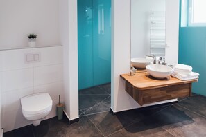 A modern bathroom with a toilet, a sink with a bowl, and a mirror. - Louis & Louise Apartments & Penthouses  (Bremen)