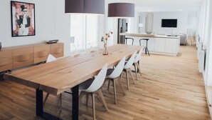Et moderne køkken med en træø, hængende lamper og et fladskærms-tv.