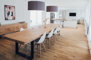 A modern kitchen with a wooden island, pendant lights, and a flat-screen TV. - Louis & Louise Apartments & Penthouses  (Bremen)