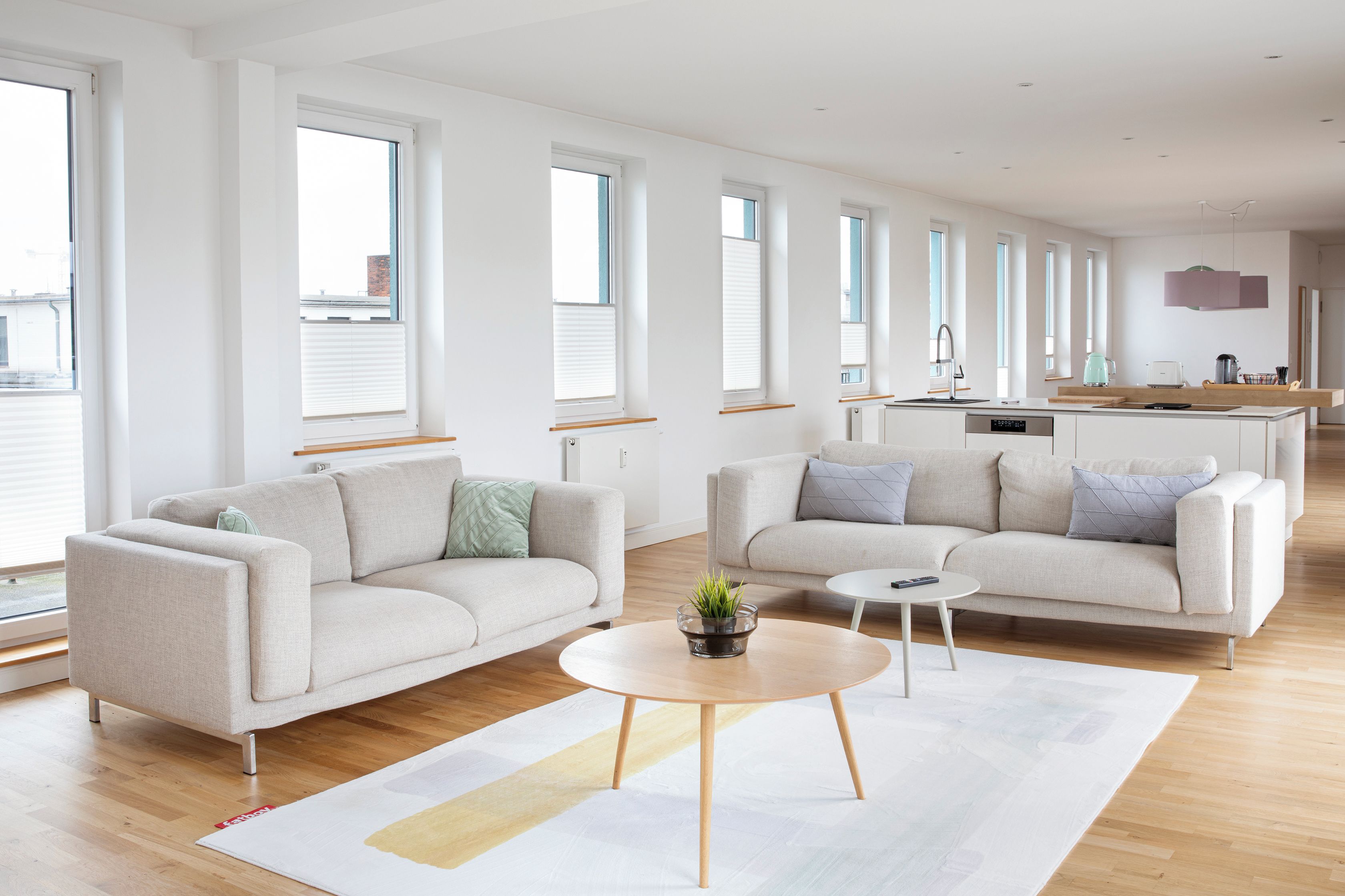 Un salon moderne avec deux canapés, une table basse et, au fond, un espace cuisine.
