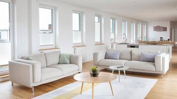 Un salon moderne avec deux canapés, une table basse et, au fond, un espace cuisine.