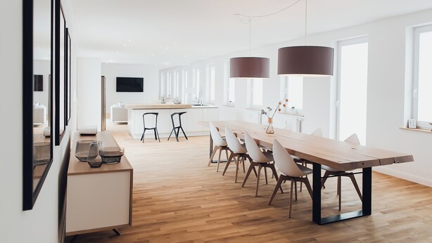 A modern kitchen with a wooden dining table, chairs, and pendant lights. - Louis & Louise Apartments & Penthouses  (Bremen)