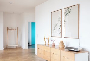 A modern interior with a wooden floor, a white wardrobe, and two abstract paintings.