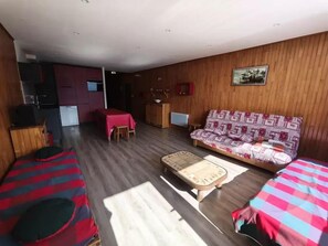 Um espaço compacto com sofá, duas camas, mesa de jantar e cozinha compacta.