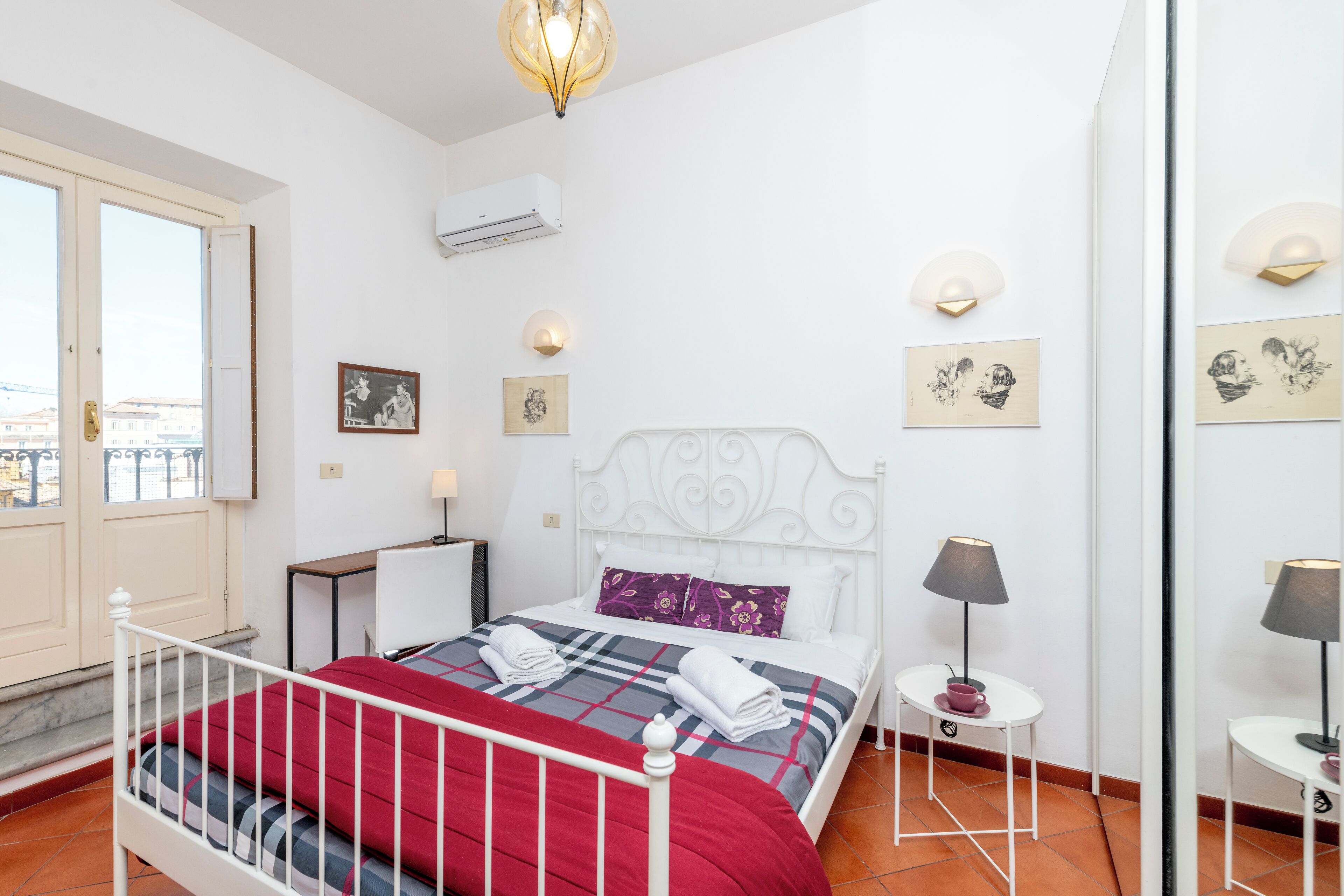 Een netjes ingerichte slaapkamer met een bed, nachtkastjes, een spiegel en kunstwerken aan de wanden.