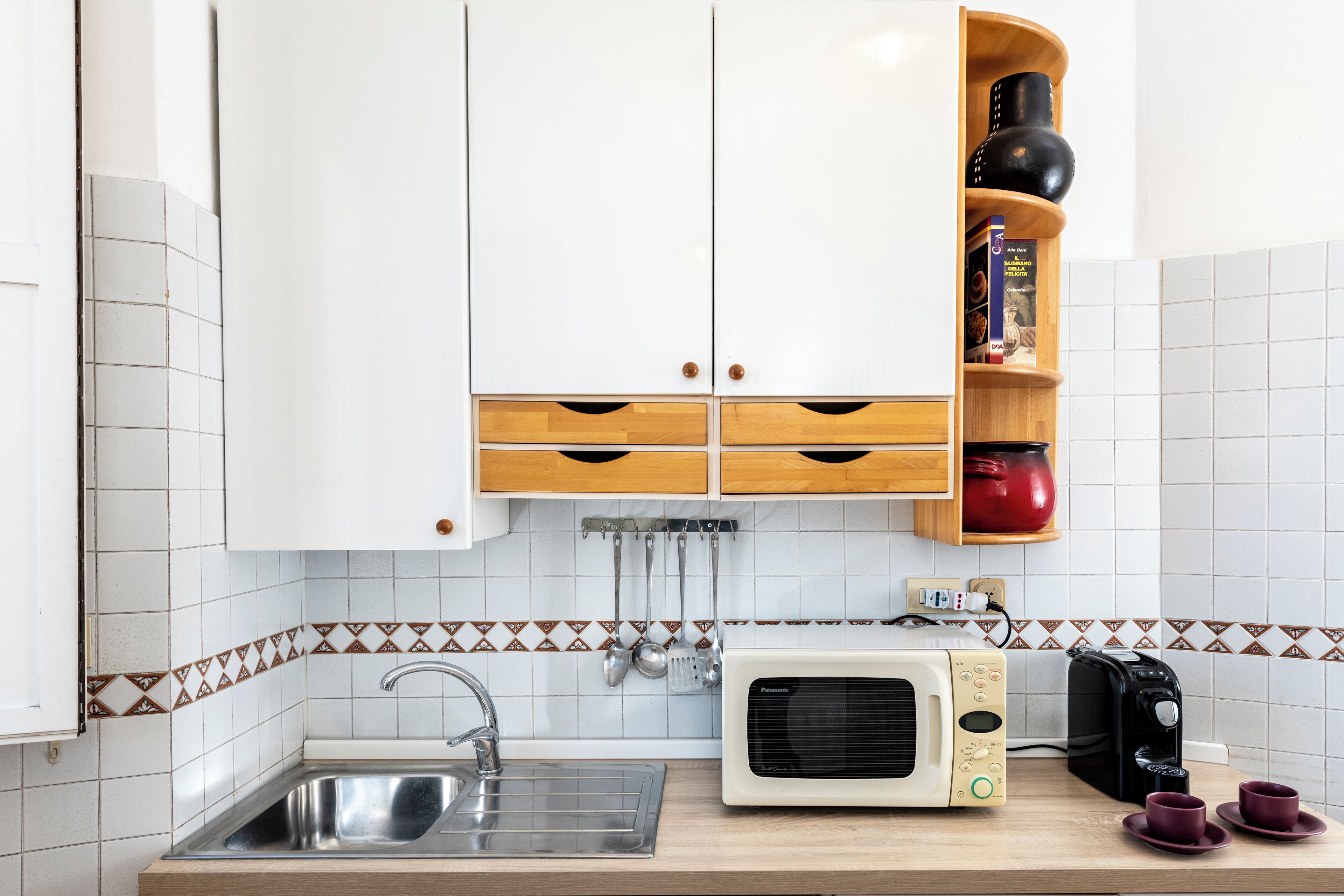 A kitchen with white cabinets, a microwave, a toaster, and a sink.