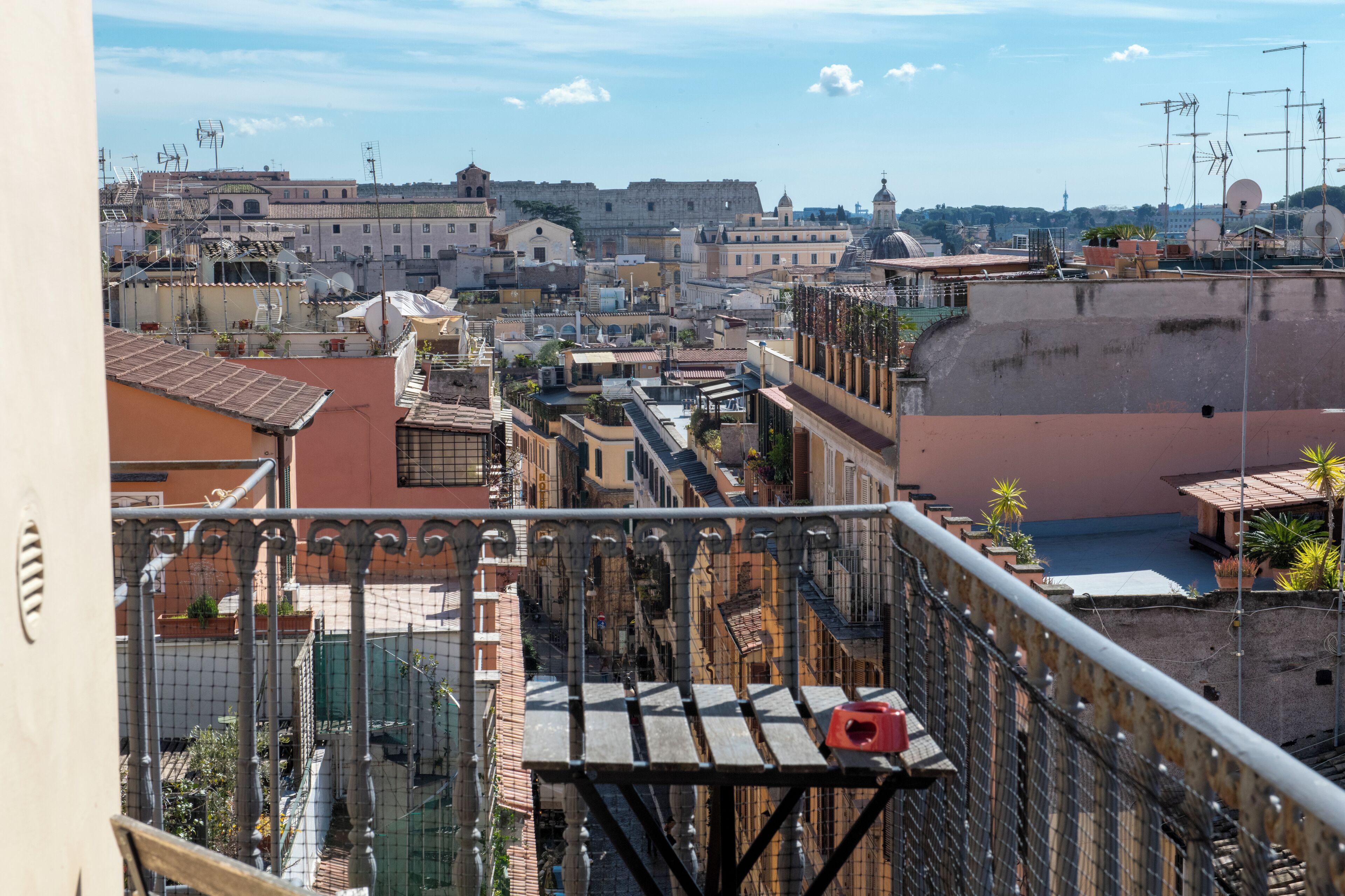 Une vue depuis un balcon donnant sur un paysage urbain, avec des bâtiments historiques, un dôme imposant et un ciel dégagé.