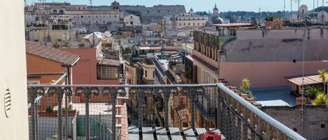 Une vue depuis un balcon donnant sur un paysage urbain, avec des bâtiments historiques, un dôme imposant et un ciel dégagé.