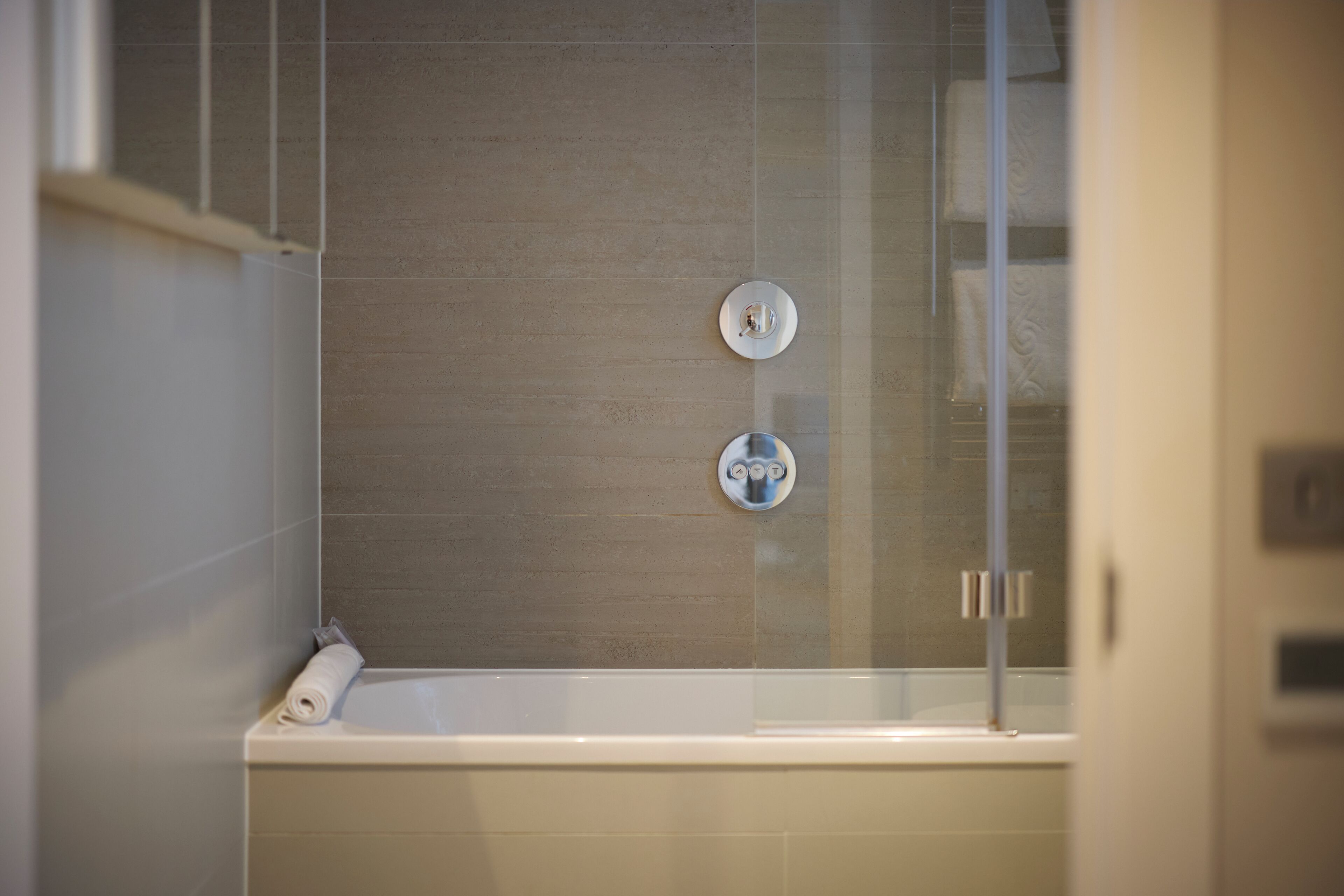 Ein modernes Badezimmer mit einer Badewanne, einem Handtuchhalter und einer Duschkabine aus Glas.
