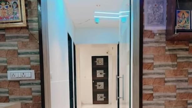 En hall med en skylt som säger ”VÄLKOMMEN”, en inramad tavla på vänster sida och en vägg med ett mönster.